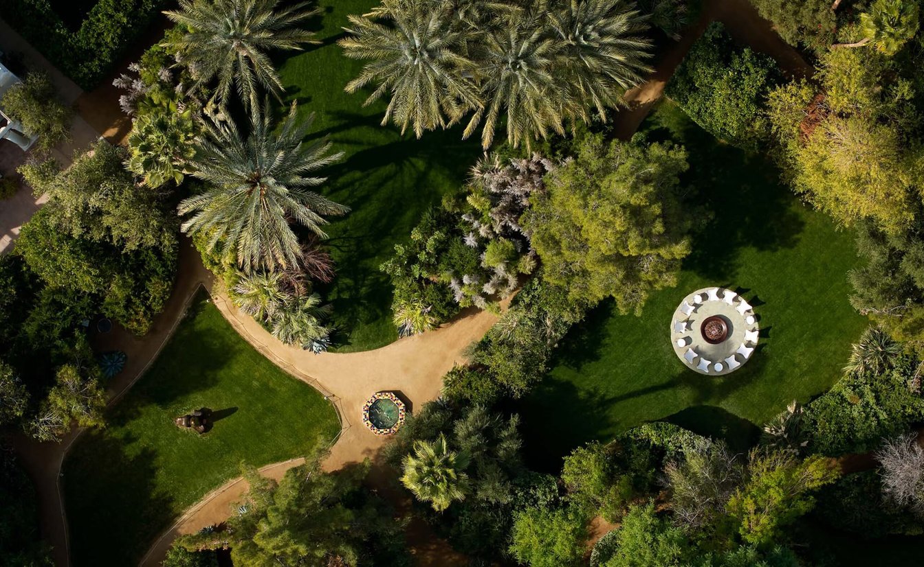 An aerial view of a lush outdoor space with a seating area, pathway, and fire pit.