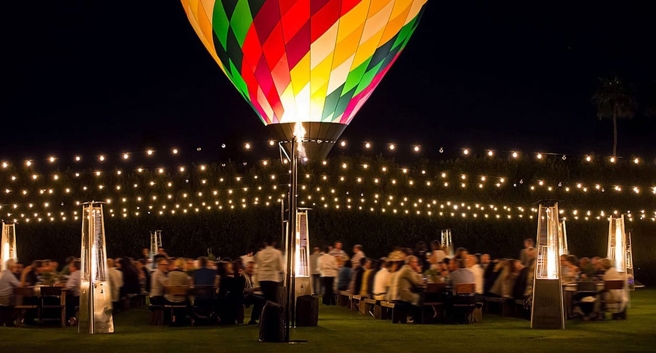 a colorful hot air balloon lights up an outdoor event space at night