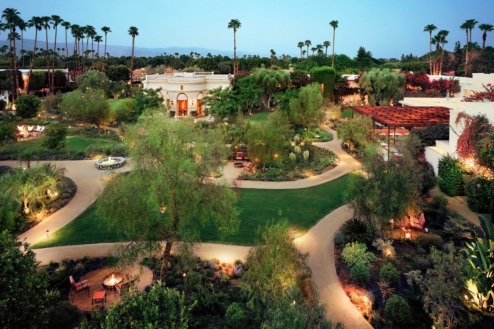 aerial view of a hotel's landscaped grounds with pathways, fire pits, and seating areas