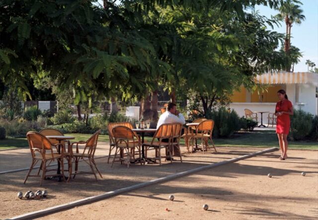 A bocce court with outdoor seating and people playing on a sunny day.