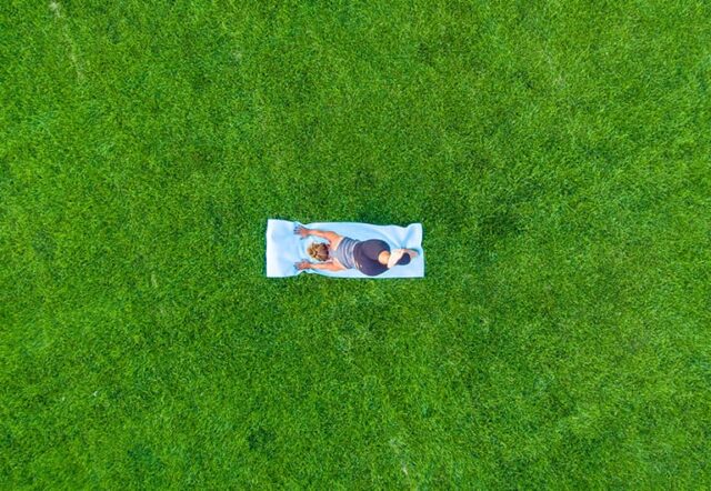 A person practicing yoga on a mat in a grassy area.