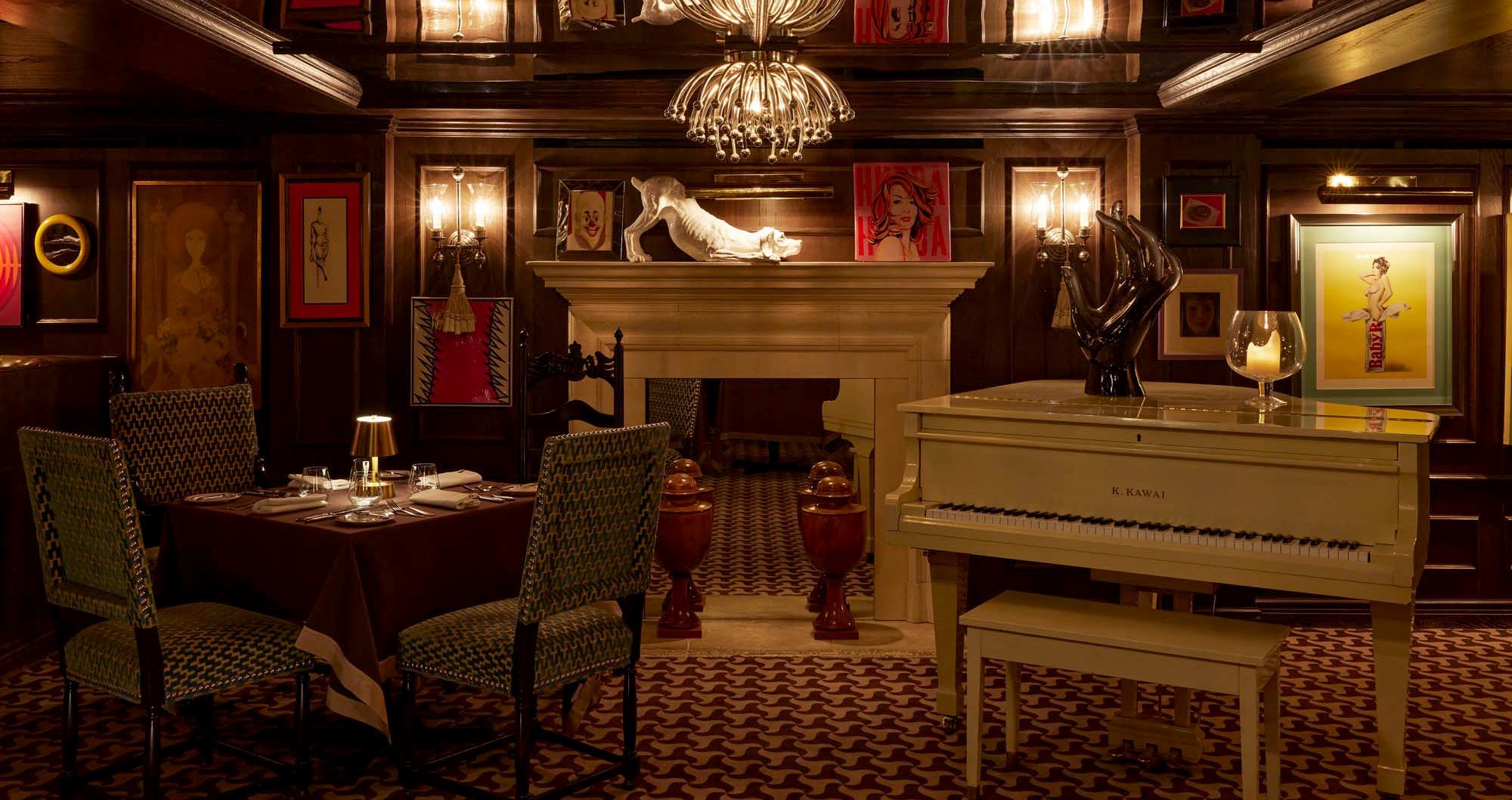 A dining area with a table set for dinner, a piano, and a fireplace.