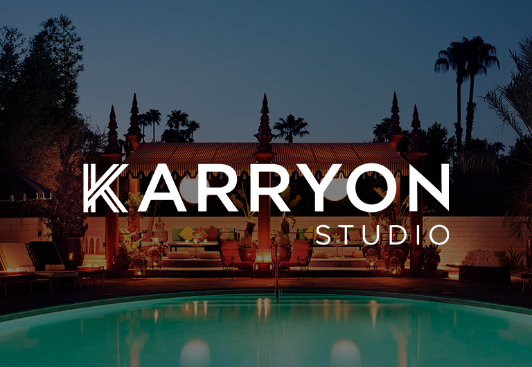 A luxurious outdoor pool area at dusk with warm lighting, lush trees, and a stylish lounge; KARRYON STUDIO is written in bold white text over the image.