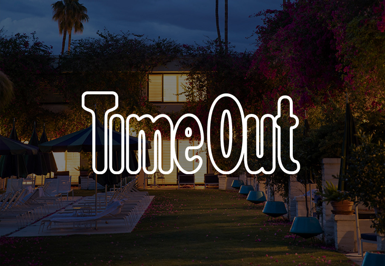 Time Out in large outlined letters overlays an outdoor pool area with empty lounge chairs, umbrellas, and lush greenery, illuminated by evening lights.